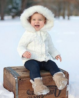 A young girl wearing a winter coat with the hood popped outside.